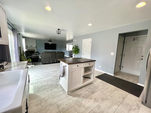 kitchen with marble finish floor, a sink, wood counters, recessed lighting, and white cabinets