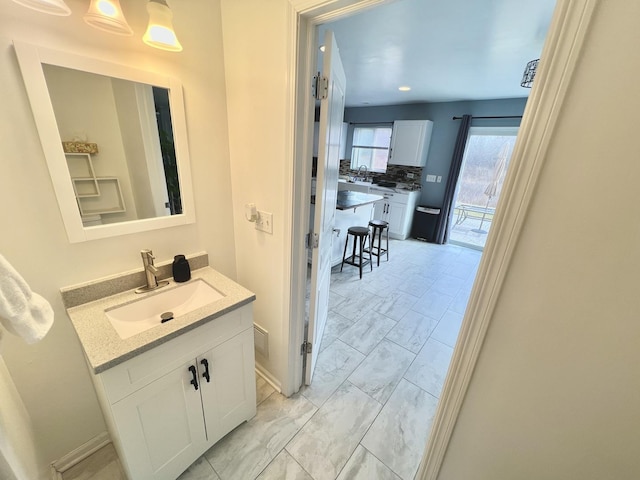 bathroom featuring baseboards, backsplash, marble finish floor, and vanity