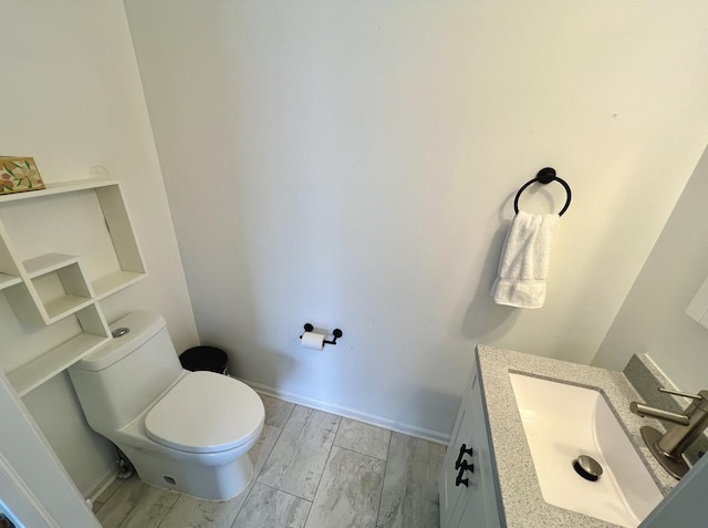 bathroom featuring toilet, vanity, and baseboards