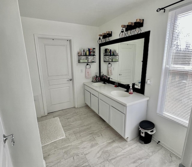 bathroom featuring double vanity, marble finish floor, and a sink