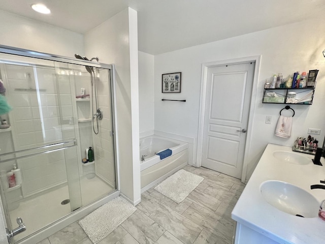 bathroom featuring a garden tub, double vanity, a stall shower, and a sink