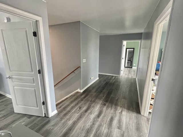 corridor with baseboards, an upstairs landing, and dark wood finished floors