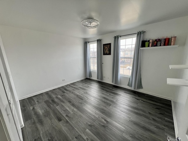 spare room with baseboards and dark wood-type flooring