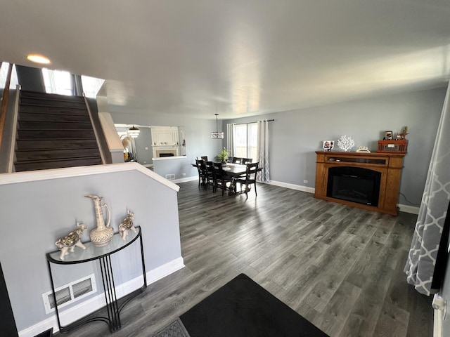 living room with stairway, wood finished floors, visible vents, baseboards, and a fireplace