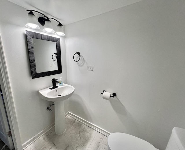 half bathroom featuring marble finish floor, toilet, and baseboards