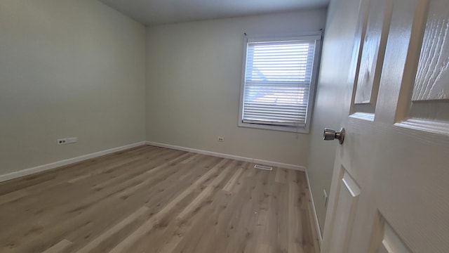 spare room featuring light wood-type flooring, baseboards, and visible vents