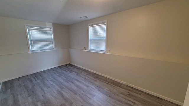 empty room with visible vents, baseboards, and wood finished floors