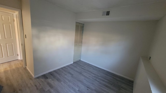 spare room featuring wood finished floors, visible vents, and baseboards