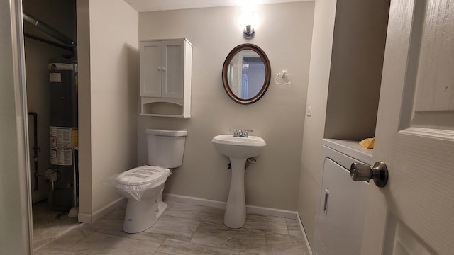 half bathroom with baseboards, washer / clothes dryer, gas water heater, toilet, and marble finish floor