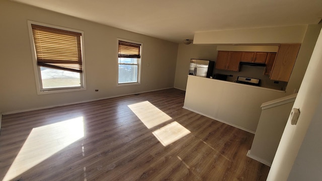 unfurnished living room featuring baseboards and dark wood-type flooring