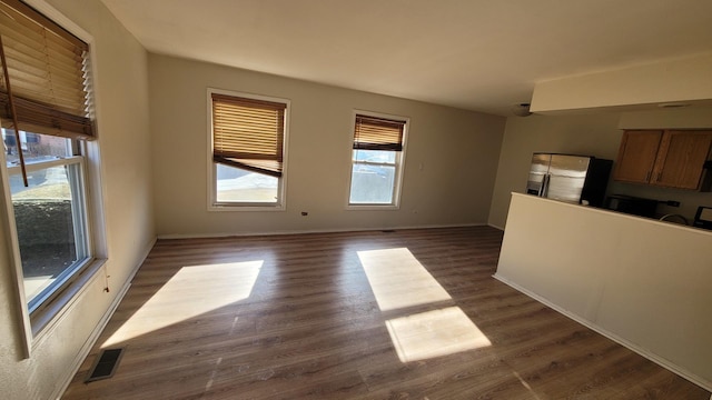 unfurnished living room featuring visible vents, dark wood-type flooring, and baseboards