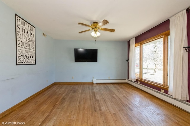 spare room featuring visible vents, a baseboard heating unit, baseboards, a ceiling fan, and wood-type flooring