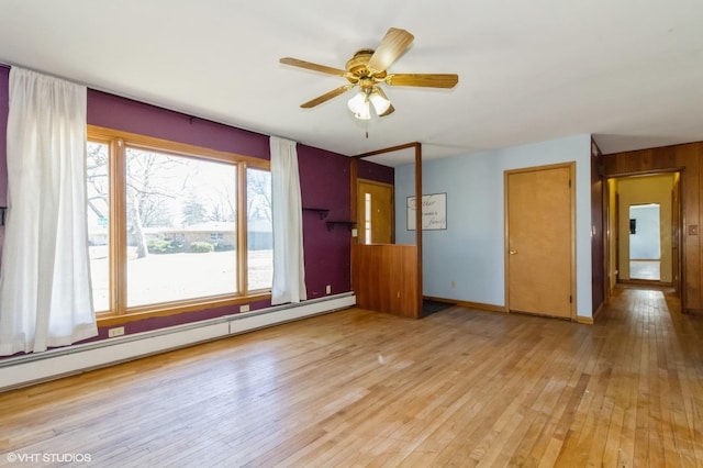 unfurnished room with light wood finished floors, baseboard heating, baseboards, and ceiling fan