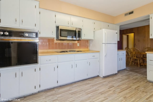 kitchen with visible vents, stainless steel appliances, light countertops, white cabinetry, and backsplash