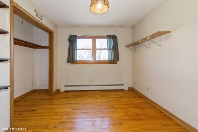 unfurnished bedroom with a closet, light wood-style flooring, baseboards, and a baseboard radiator