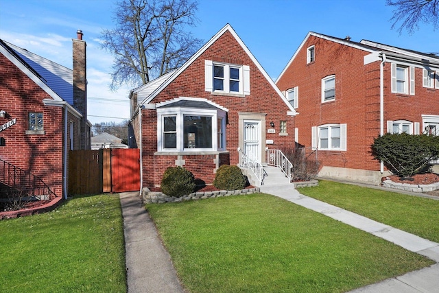 bungalow-style house featuring a front lawn, fence, and brick siding