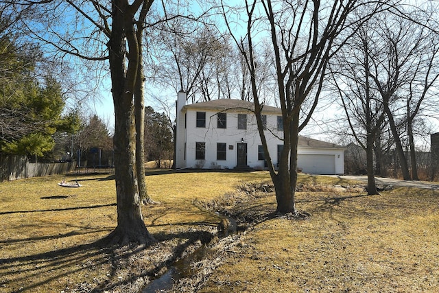 view of front facade with a garage, a chimney, a front yard, and fence