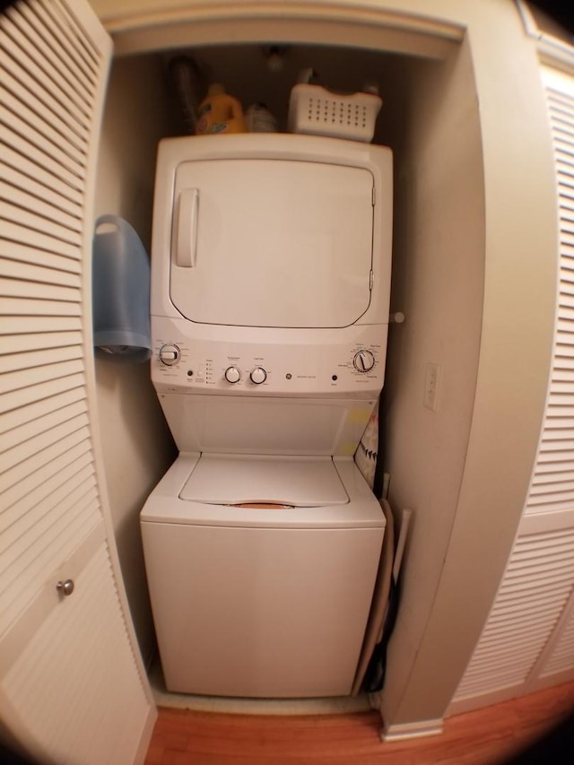 laundry area featuring laundry area, stacked washer / dryer, and wood finished floors