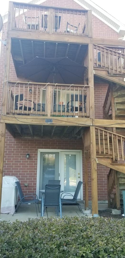 rear view of property with brick siding and a balcony