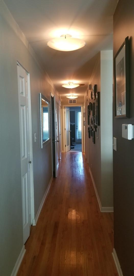 hall featuring visible vents, wood finished floors, and baseboards