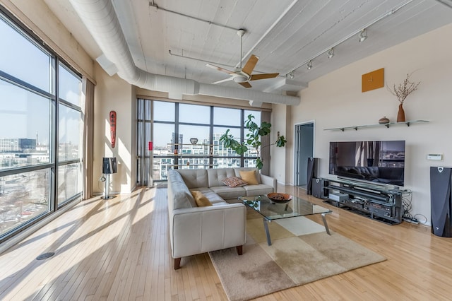 living area featuring track lighting, a view of city, ceiling fan, and hardwood / wood-style floors