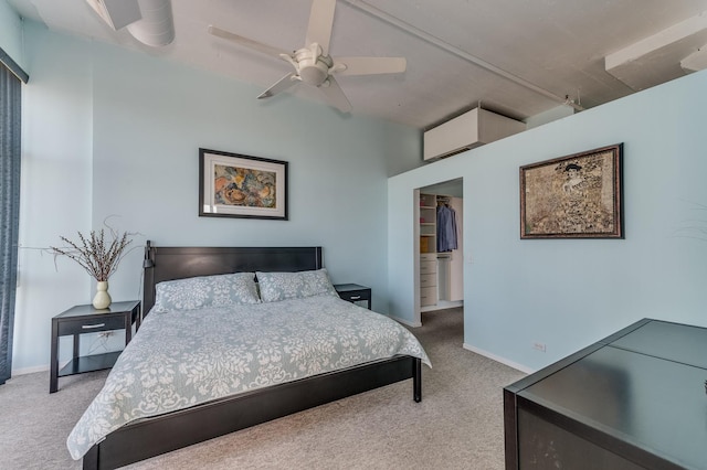 carpeted bedroom featuring a walk in closet, a ceiling fan, baseboards, and a closet