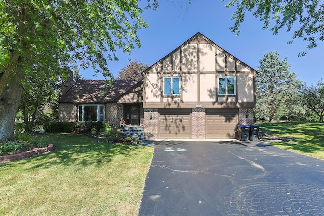 tudor house with aphalt driveway, an attached garage, a front lawn, and brick siding