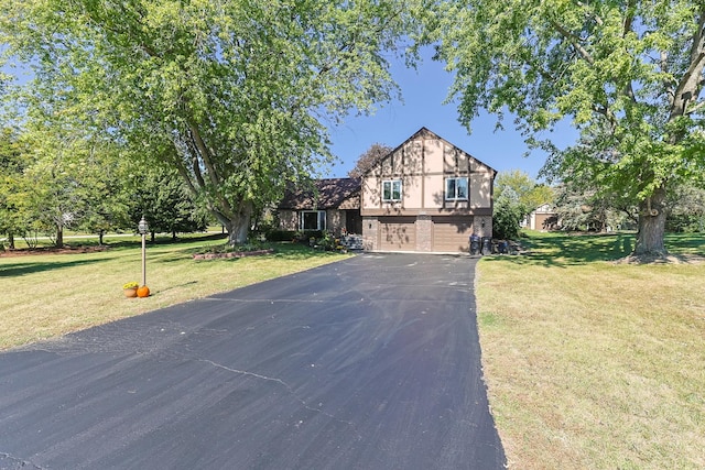 view of front of house featuring aphalt driveway, brick siding, an attached garage, and a front yard