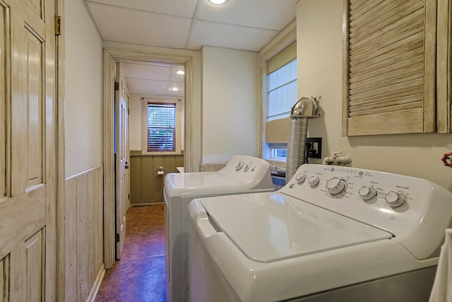 washroom with a wainscoted wall, wooden walls, dark floors, and washer and clothes dryer