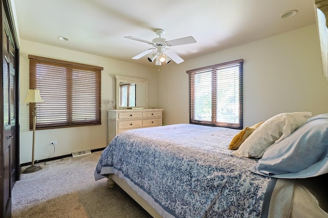 bedroom with visible vents, light colored carpet, a ceiling fan, and baseboards