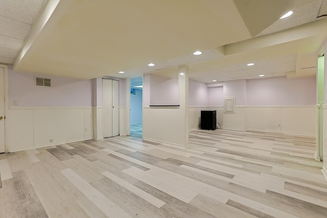 finished basement featuring light wood finished floors, visible vents, wainscoting, and recessed lighting