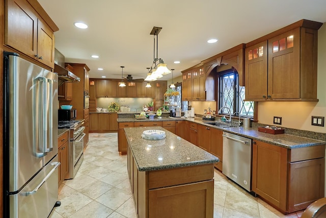 kitchen with a ceiling fan, a sink, high quality appliances, brown cabinets, and a center island