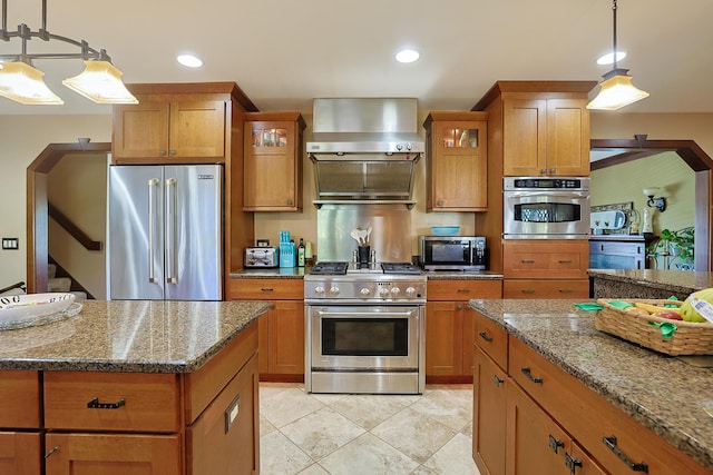 kitchen with brown cabinetry, light stone countertops, glass insert cabinets, decorative light fixtures, and high quality appliances