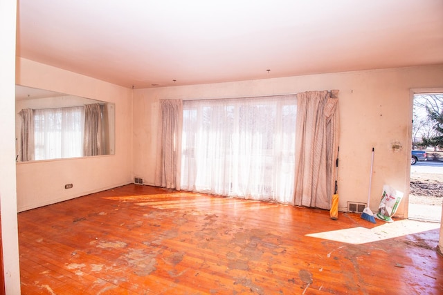 unfurnished room featuring visible vents, plenty of natural light, and hardwood / wood-style flooring