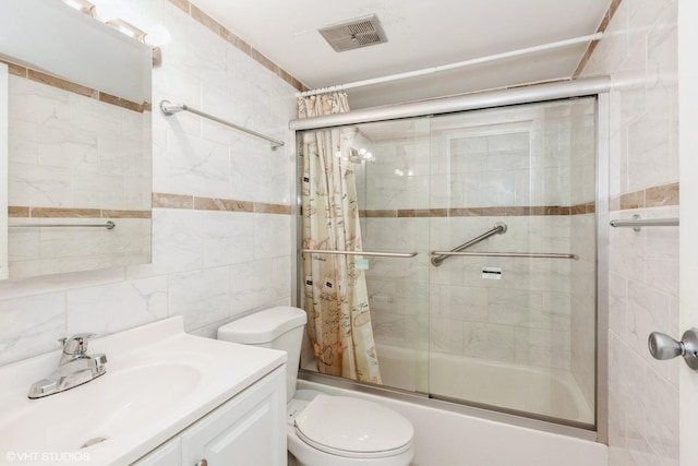 full bath with visible vents, toilet, vanity, combined bath / shower with glass door, and tile walls