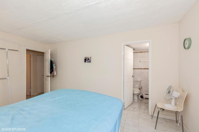 bedroom with baseboards, baseboard heating, and ensuite bathroom