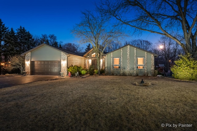 view of front of property featuring driveway, a front yard, and an attached garage