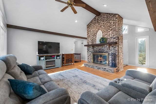 living room with beam ceiling, wood finished floors, a fireplace, and ceiling fan