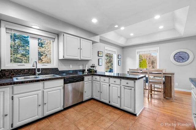 kitchen featuring a sink, stainless steel dishwasher, a peninsula, and white cabinetry