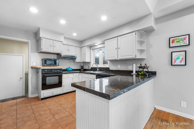 kitchen with under cabinet range hood, open shelves, a sink, appliances with stainless steel finishes, and a peninsula