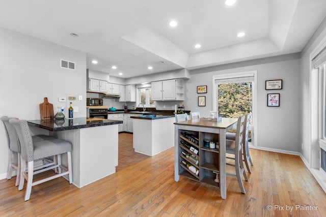 kitchen with visible vents, a peninsula, a sink, and open shelves