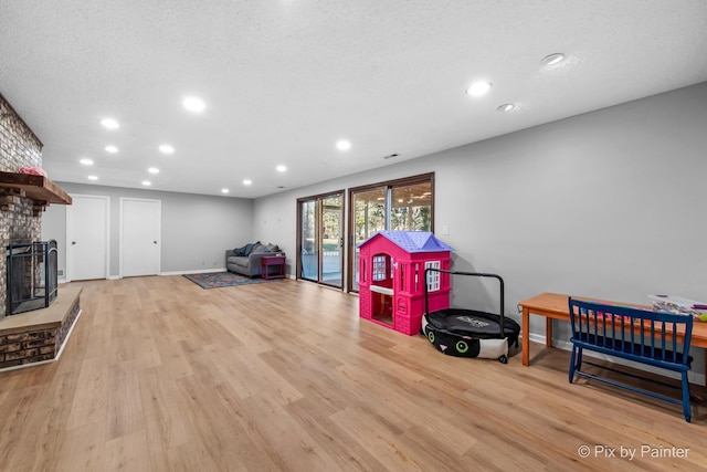 rec room featuring recessed lighting, light wood-type flooring, baseboards, and a brick fireplace