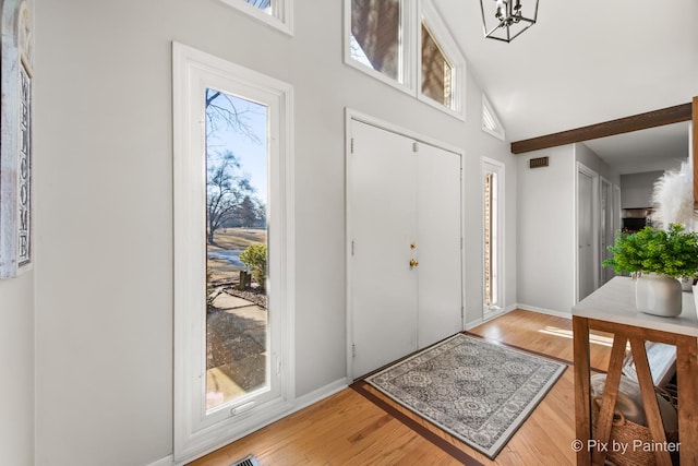 entryway featuring light wood finished floors, visible vents, high vaulted ceiling, and baseboards