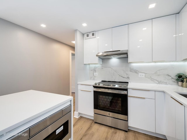 kitchen featuring light countertops, stainless steel range with electric stovetop, under cabinet range hood, white cabinetry, and modern cabinets