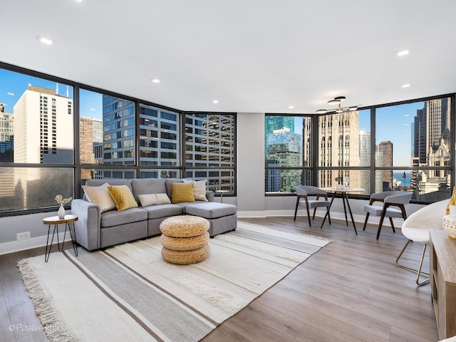 living room with recessed lighting, a view of city, baseboards, and wood finished floors