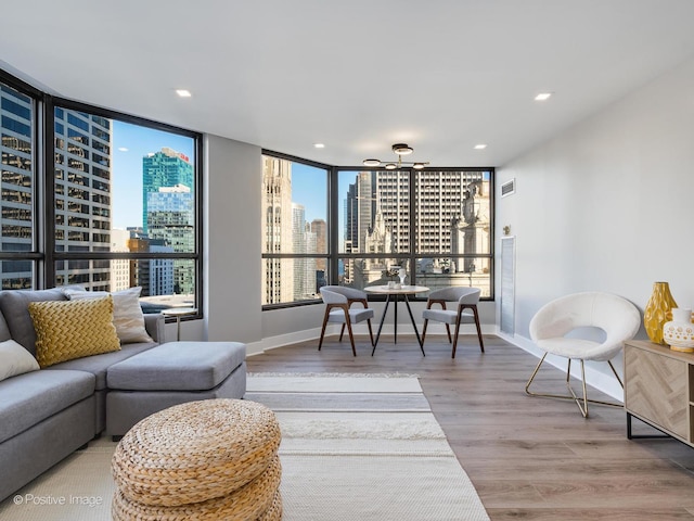 living room featuring a city view, recessed lighting, baseboards, and wood finished floors