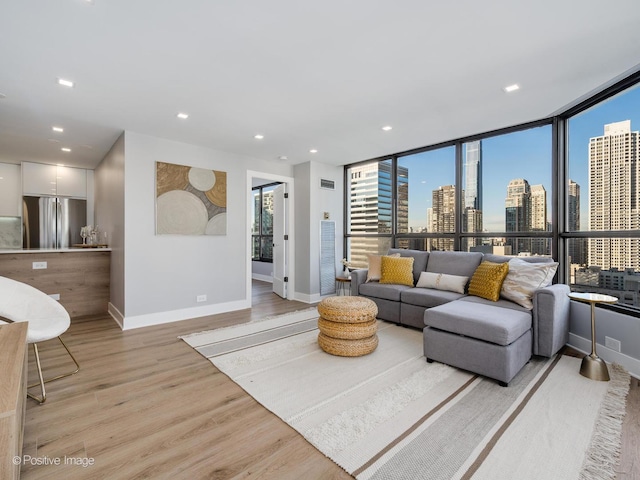 living area with visible vents, a view of city, recessed lighting, light wood finished floors, and baseboards