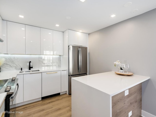 kitchen featuring a sink, stainless steel appliances, white cabinets, modern cabinets, and light wood-type flooring