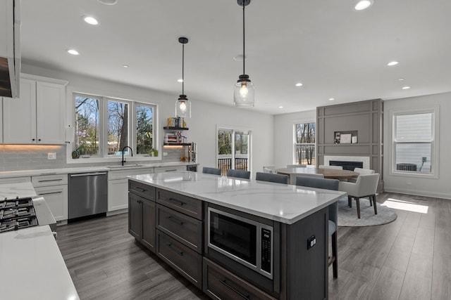 kitchen with tasteful backsplash, a breakfast bar, appliances with stainless steel finishes, white cabinets, and a sink