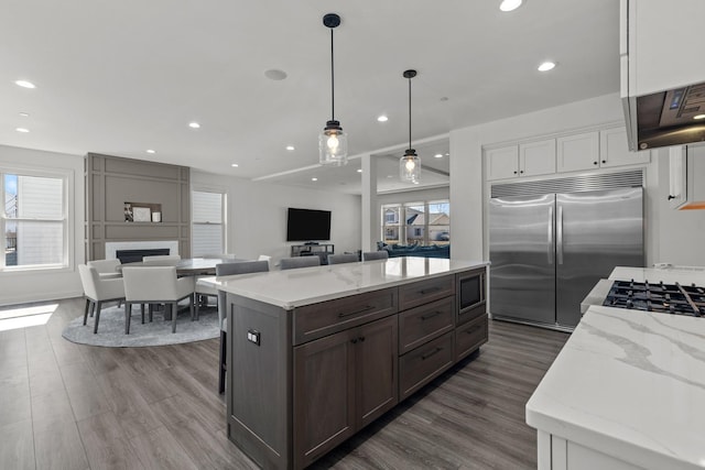 kitchen featuring white cabinetry, plenty of natural light, dark wood finished floors, and stainless steel built in fridge